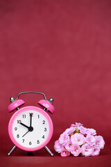 Pink flowers and retro alarm clock. Spring or summer vertical red background with copy space.