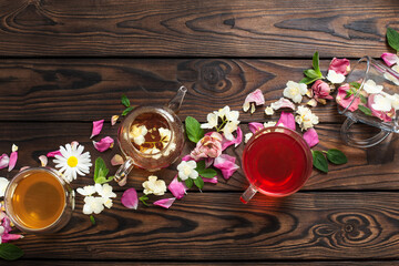 various teas with herbs and flowers on a dark wooden table, top view
