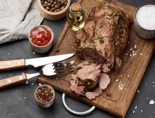 Baked pork collar with spices on a wooden board, delicious and juicy meat