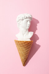 Waffle cone with ancient head on pink background