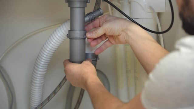 Plumber repairs plumbing pipes in kitchen sink. Removing blockage clog in drain pipe. Replacement of plumbing pipe. Close-up