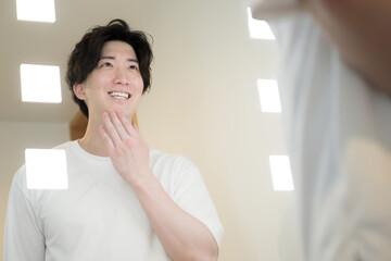 髭やスキンケアを鏡で確認する男性