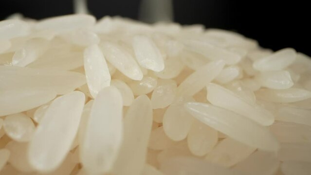 Pouring of jasmine rice in a way that emulates the calming effect of ripples in water. As the rice is released onto the floor. Macro video. Thailand's jasmine rice is the best rice in the world. 4K