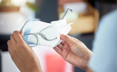 Hands, vision and a person cleaning glasses in her office with a tissue for clear eyesight closeup. Wiping, prescription lenses and frame with an adult holding eyewear to clean using a wet wipe