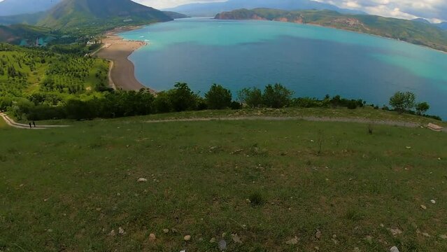 Paragliding launch at Amirsoy ski slope and Charvak lake in Uzbekistan. Paraglider lifts open glider with the inscription independence and take off. raises wing, and lifts off from the ground.