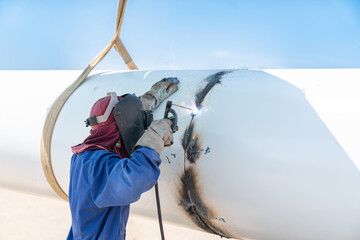 Close up worker welding pipe of water tower.