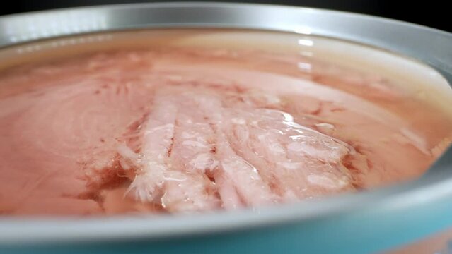 In this macro video, you can see chunks of light tuna fish packed in a can. The flesh appears pinkish and delicate, with a slightly mild flavor.