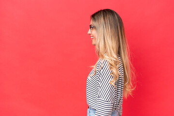 Young Uruguayan woman isolated on red background laughing in lateral position