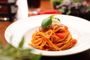 Tomato spaghetti with basil and cheese on a white plate. Italian pasta, bolognese, horizontal view
