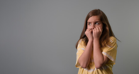 Scared child. banner on a gray background. Teen girl in a frightened pose looks with fear