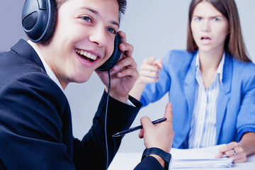 I can't listen this bullshits. Young worker in headphones laughing and ignoring his boss