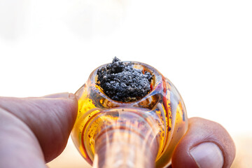 glass marijuana weed pipe held by hand after consuming it. Closeup first person view of man smoking...