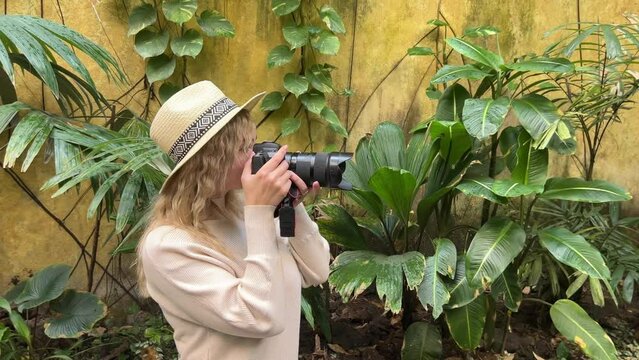 attractive woman taking pictures on a professional camera in a botanical garden