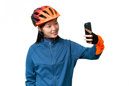 Young cyclist woman over isolated chroma key background making a selfie
