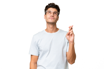 Young caucasian handsome man over isolated background with fingers crossing and wishing the best