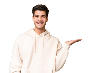 Young caucasian handsome man over isolated background holding copyspace imaginary on the palm to...