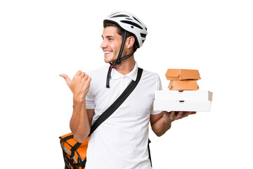 Young caucasian man with thermal backpack over isolated background pointing to the side to present a product