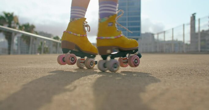 Female legs in cute yellow rollerskates spin in one place, do tricks. Bright colourful and summer outfit. Concept fun activity for kids, empowering females to do sports.Funky sport or fitness outdoors