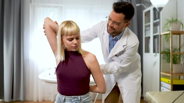 A chiropractor is treating a young woman as a patient in his office.