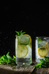 Cold lemonade with mint and lemon and ice on a dark background