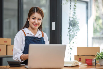 Portrait of Asian young woman SME working with a box at home the workplace.start-up small business owner, small business entrepreneur SME or freelance business online and delivery concept.