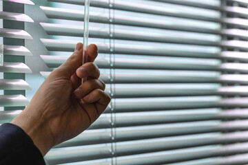 Office blinds. close up view of man opening modern blinds to control lighting range in office....