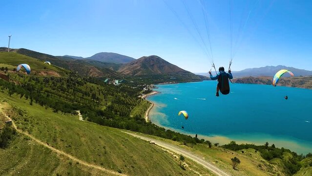 paragliding in Uzbekistan. back view from gopro man paraglider flying over the Amirsoy ski slope and Charvak lake. Extreme and active types of recreation. High quality FullHD footage
