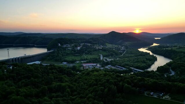 Panoramic view from the drone during sunset, on the Solińskie lake overlooking the modern gondola cable car with the lookout tower over the Solina water dam, in the Polish Bieszczady Mountains, Poland