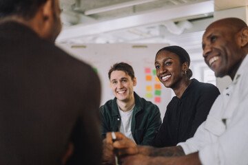 Happy students and male professor sitting in innovation lab