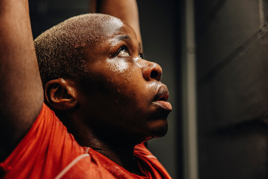 Female athlete looking up with arms raised while working out in gym