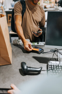 Midsection of mature man scanning credit card on reader at checkout in electronics store