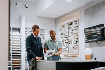 Salesman discussing with mature man over brochure at store