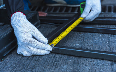 Builder using measuring tape measure steel frame in construction site, Welder Concept