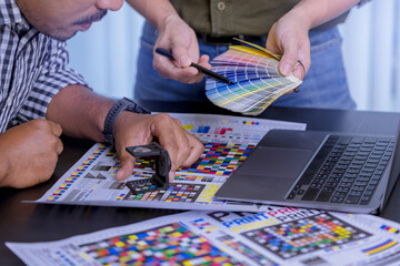 Crop image of worker checking print quality of media graphics proof print and color tone in printing industry. Selected focus