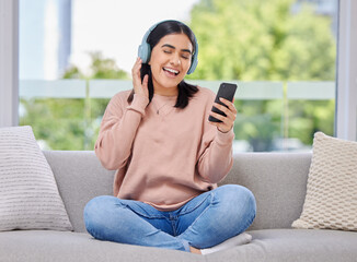Woman, headphones and phone for singing on sofa for happiness, relax and sound in home living room....
