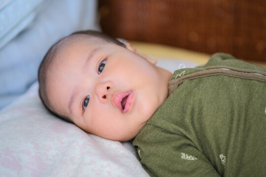 Cute and healthy chubby three months old Asian baby boy in his bed after bath