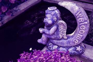 Surreal Pop Art styled Purple Sculpture of an Angel Sitting on Crescent Moon in the Garden