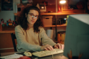 Portrait of young programmer in eyeglasses looking at camera while developing new software on...