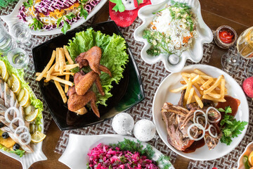 Flat lay of Delicious Christmas themed dinner table with roasted meat steak, appetizers and desserts. Top view.