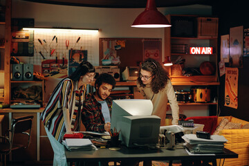Group of young people sitting at table in front of computer and discussing new project