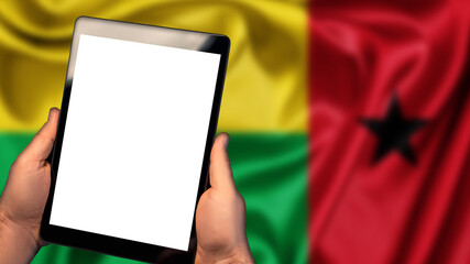 Man hold tablet phone pc gadget with white blank screen, copy space for text, image or message. Flag of Guinea-Bissau country on background. Technology, information, business