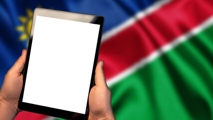 Man hold tablet phone pc gadget with white blank screen, copy space for text, image or message. Flag of Namibia country on background. Technology, information, business
