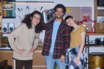Portrait of teenagers smiling at camera and listening to music on tape recorder standing in garage