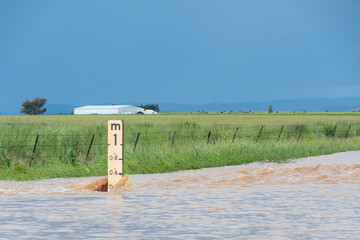 Close up of flood depth indicator on flooded road surrounded by water