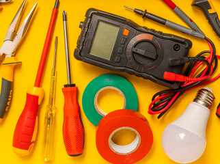 Electrician equipment on yellow background with copy space.Top view.Electrician tool set.Multimeter, tester,screwdrivers,cutters,duct tape,lamps,tape measure and wires.Flet lay. © Avocado_studio