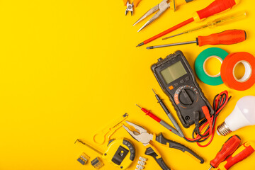 Electrician equipment on yellow background with copy space.Top view.Electrician tool set.Multimeter, tester,screwdrivers,cutters,duct tape,lamps,tape measure and wires.Flet lay. © Avocado_studio
