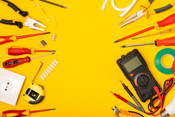 Electrician equipment on yellow background with copy space.Top view.Electrician tool set.Multimeter, tester,screwdrivers,cutters,duct tape,lamps,tape measure and wires.Flet lay. © Avocado_studio
