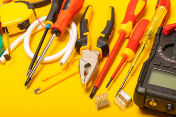 Electrician equipment on yellow background with copy space.Top view.Electrician tool set.Multimeter, tester,screwdrivers,cutters,duct tape,lamps,tape measure and wires.Flet lay. © Avocado_studio