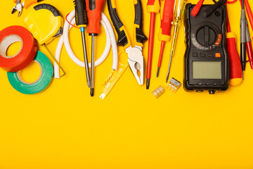 Electrician equipment on yellow background with copy space.Top view.Electrician tool set.Multimeter, tester,screwdrivers,cutters,duct tape,lamps,tape measure and wires.Flet lay. © Avocado_studio