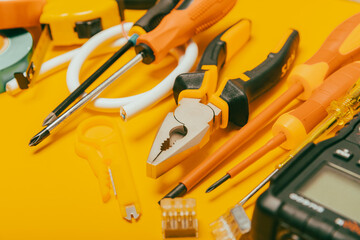 Electrician equipment on yellow background with copy space.Top view.Electrician tool set.Multimeter, tester,screwdrivers,cutters,duct tape,lamps,tape measure and wires.Flet lay. © Avocado_studio